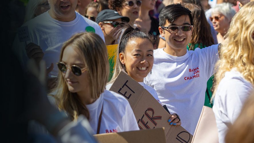 Two adults at a peaceful protest wearing Bank on Change shirts 888x500 1