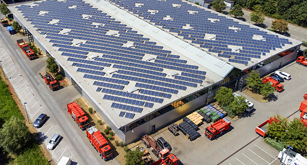 Large industrial building, solar panels and trucks aerial view